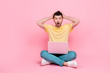 Obraz na płótnie Canvas Photo of impressed worried nervous man sit open mouth omg panic alert 404 lost device gadget isolated on pink color background