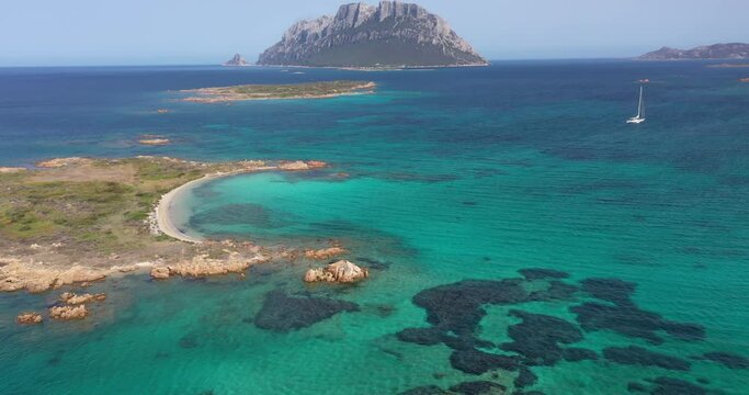 Aerial view of the steep limestone and granite cliffs of Tavolara Island surrounded by a clear and turquoise sea in Sardinia, Italy.