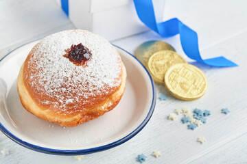 Happy Hanukkah. Hanukkah sweet doughnuts, gift boxes, white candles and chocolate coins on white wooden background. Image and concept of jewish holiday Hanukkah. Top view.