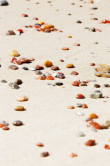 Sea stones amber yellow colored on natural fine beige  sand shore background, copy space. Natural colorful pebbles, monochrome Minimal nature summer landscape, beautiful beach, selective focus