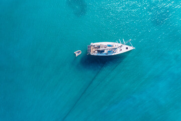 Yacht on lagoon at sunny day. Sailing boat. Yacht in the sea, aerial photography drone. Amazing yacht or sailing boat with a turquoise and transparent sea. Top view of the sailing boats in blue lagoon