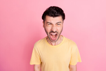 Obraz premium Portrait of angry screaming mad man with stylish haircut wear yellow t-shirt loud shouting open mouth isolated on pink color background