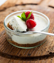 Cheesecake served in a glass with a biscuit base and decorated with fruit.