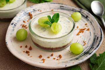 Cheesecake served in a glass with a biscuit base and decorated with fruit.