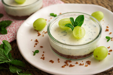 Cheesecake served in a glass with a biscuit base and decorated with fruit.
