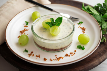 Cheesecake served in a glass with a biscuit base and decorated with fruit.