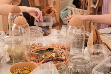 Herbal tea collection. Glass jars with lids. Master class on cooking, training. The hands of the participants are large against the background of jars and bowls with herbs. Ecological, clean.