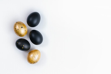 Eggs painted gold and black on white background. Minimal Easter concept. Golden luxury backdrop with copy space for text.