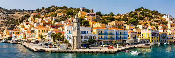 View on Symi (Simi) island harbor port, classical ship yachts, houses on island hills, Aegean Sea bay. Greece islands holidays vacation travel tours from Rhodos island. Symi, Greece,  Dodecanese.