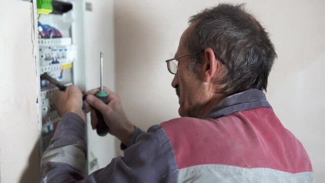 An electrician assembles a switchboard in a new building apartment.