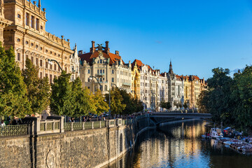 Obraz premium Scenic embankment in Prague city; Historical center of Prague, buildings and landmarks of old town, Prague, Czech Republic. Embankment of the Vltava river in Prague, the capital of Czechia.