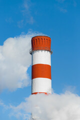 Pollution of the environment, ecology and air. Withdrawal of combustion products of soot, smoke and gases from the pipe of an industrial plant into the atmosphere against the background of a blue sky