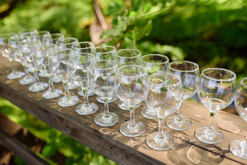 Many empty clean glasses for guests at the festive wedding buffet table in nature