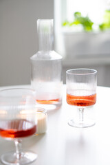 Rose wine in trendy ribbed wineglasses and decanter on white table