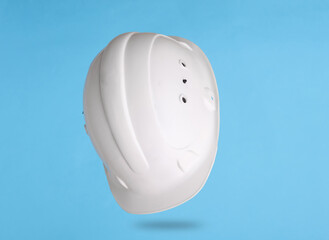 White construction helmet levitating on a blue background with shadow