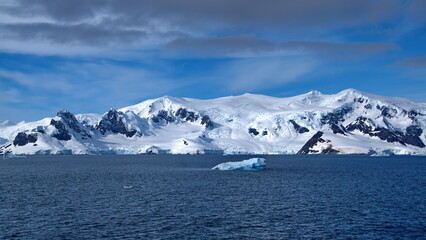 Fototapeta na wymiar Iceberg floating in front of a snow covered mountain at Portal Point, Antarctica