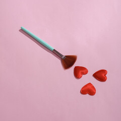 Makeup brush with hearts on a pink background. Love concept, valentine's day, february 14th celebration, creative layout