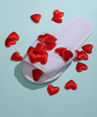 White slippers with hearts on blue background. Love concept, valentine's day, february 14th celebration, creative layout