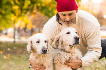Middle-aged man embracing his two dogs, golden retriever.