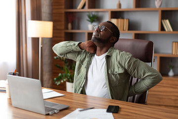Unhappy despair middle aged african american businessman in glasses suffering from back pain at...