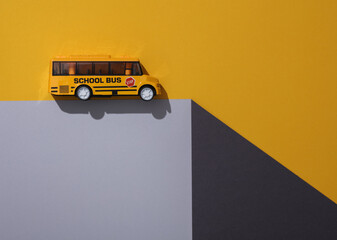 Toy school bus on a paper cube. Optical illusion. Geometric composition. Minimalistic creative...