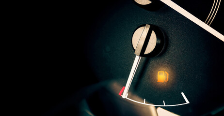 Low fuel indicator light on car dashboard, panoramic banner with copy space on black background