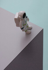 Toy astronaut on paper cube. Optical illusion. Geometric composition. Minimalistic creative layout