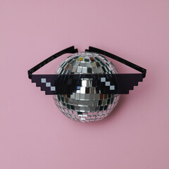 Disco ball with Pixelated 8 bit sunglasses on pink background
