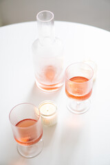 Rose wine in trendy ribbed wineglasses and decanter on white table