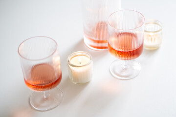 Rose wine in trendy ribbed wineglasses and decanter on white table