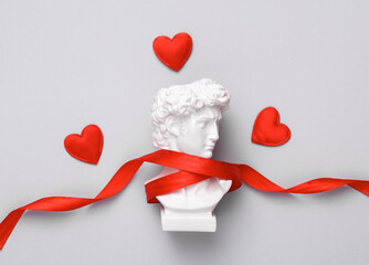 David bust  wrapped in ribbon with hearts on a gray background. Valentine's Day, February 14