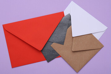Envelopes of different colors and shapes on purple background