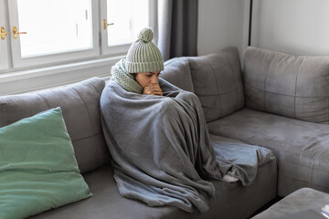 Freezing Woman Covered With Warm Blanket Sitting On Couch In Living Room