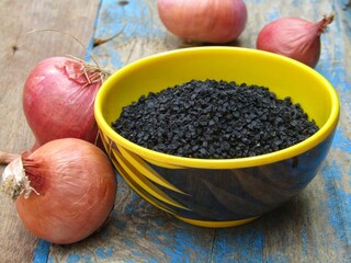 Onion seeds in a bowl on old wooden background 