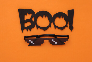 Slogan boo! with pixel sunglasses on an orange background. Halloween concept