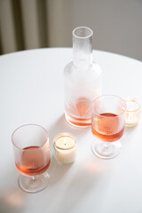Rose wine in trendy ribbed wineglasses and decanter on white table