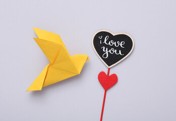 Origami dove with valentine on a stick, gray background. Valentine's day concept