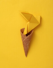 Yellow origami dove in waffle cone on a yellow background. Peace symbol, no war