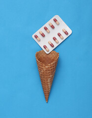 Wafer cone with a blister of pills on a blue background