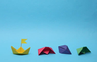 Paper colored boats on a blue background. Business, leadership concept