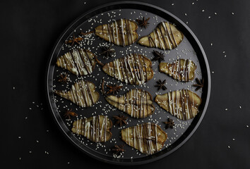 dried pears decorated with white and black chocolate and sesame seeds on a black tray and a dark background. for postcards menu labels calendars signs and stands
