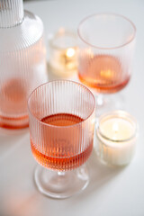 Rose wine in trendy ribbed wineglasses and decanter on white table