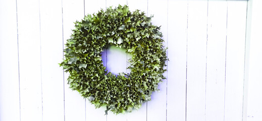 green wreath decoration of leaves on the background of a white wall of planks, floral background