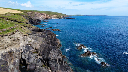 Farm fields on the rocky shore of the Celtic Sea, south of Ireland, County Cork. Beautiful coastal area. Turquoise waters of the Atlantic. Picturesque stone hills. Aerial photo. Drone point of view.