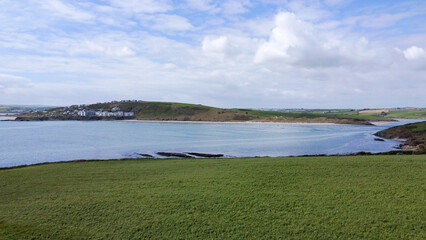 Thick green grass on a hill near the sea bay. Cloudy sky over Clonakilty Bay, seascape. Aerial photo. Drone point of view.