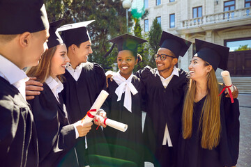 Live photo of happy talking group graduate people with diplomas after ceremony in campus. They are...