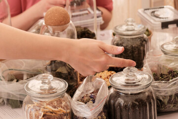 Herbal tea collection. Glass jars with lids. Master class on cooking, training. The hands of the participants are large against the background of jars and bowls with herbs. Ecological, clean.