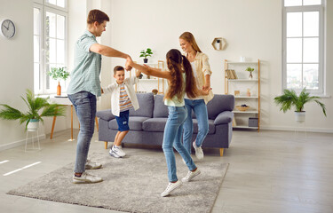 Happy family with two children are playing leading a round dance at home in living room in weekend....