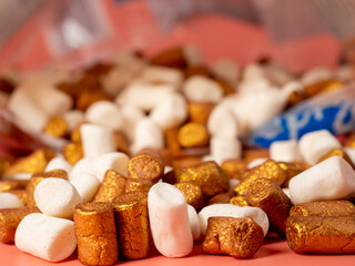 Mini marshmallows on a pink background. Marshmallow gold and white.