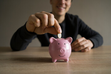 Young man with a piggy pank, takes care about his savings